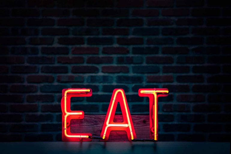 Eat logo voor een donkere muur.