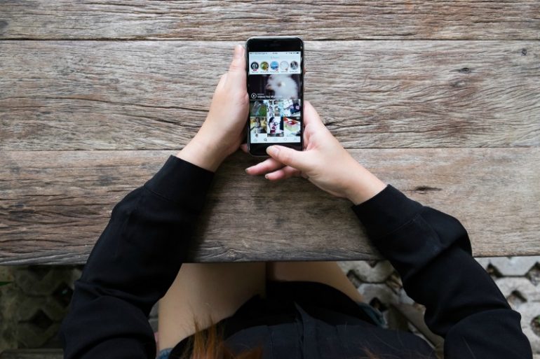 Foto van iemand die op zijn telefoon naar Instagram kijkt.