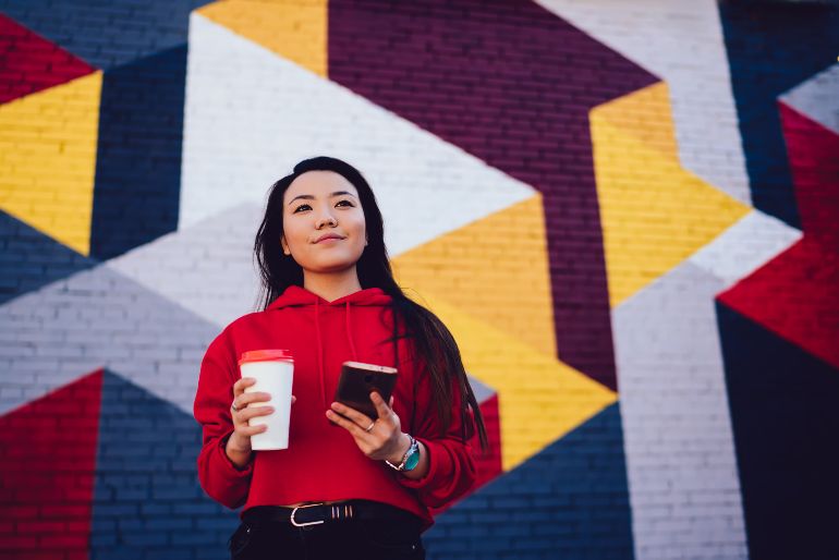 Millennial met telefoon en koffie to go.