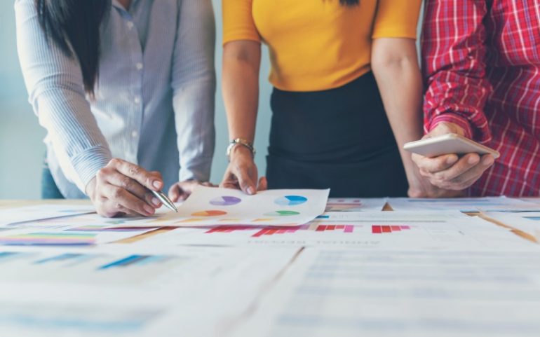 Collega's om de tafel kijken naar rapportages met diagrammen en grafieken