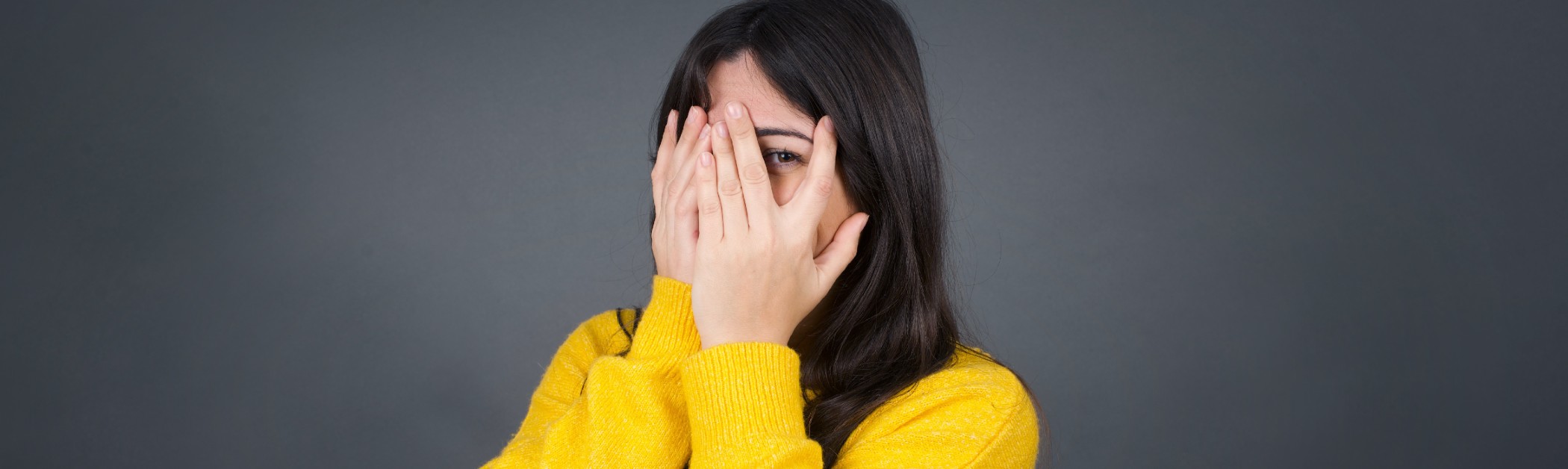 vrouw gluurt door haar handen