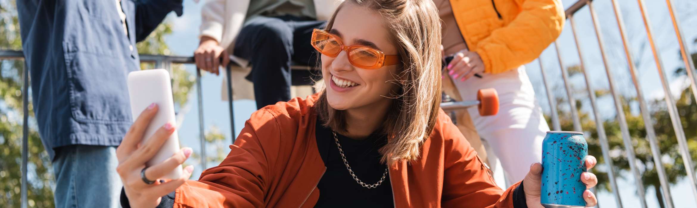 Groep jongeren waarvan vrouw op de voorgrond naar haar telefoon kijkt